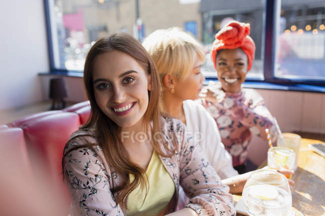 Портрет улыбающейся молодой женщины в солнечном ресторане с друзьями — стоковое фото