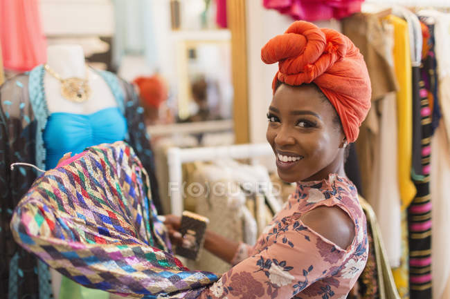 Retrato sonriente, mujer joven con confianza en las compras de pañuelos en la tienda de ropa - foto de stock