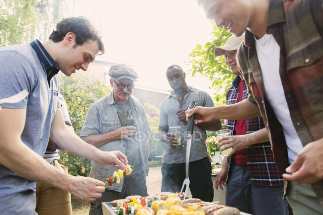 Male friends standing around barbecue grill in backyard — Stock Photo