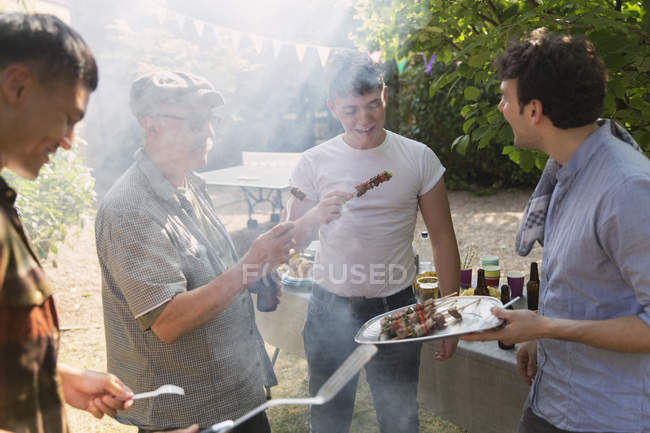 Male friends enjoying barbecue in backyard — Stock Photo