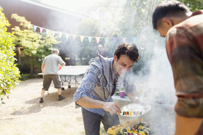 Masculino amigos churrasco no ensolarado quintal — Fotografia de Stock