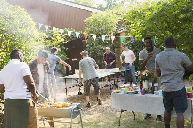 Друзья играют в пинг-понг, наслаждаются барбекю на заднем дворе — стоковое фото