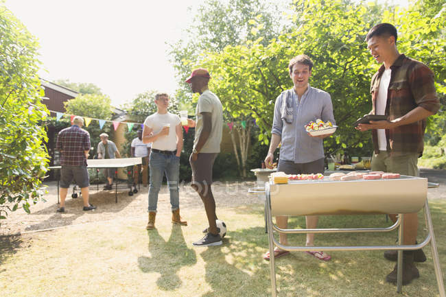 Männliche Freunde grillen im sonnigen Sommergarten — Stockfoto