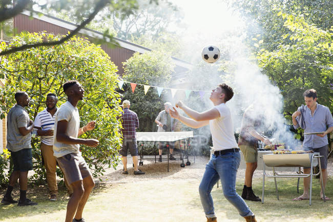 Amis masculins jouant au football et au ping-pong, profitant d'un barbecue dans la cour — Photo de stock
