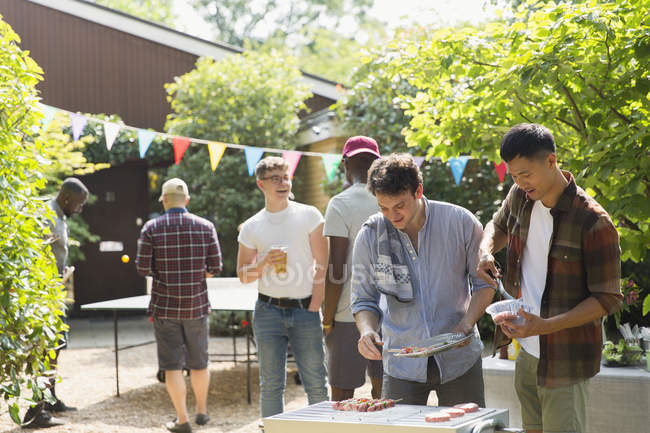 Masculino amigos aproveitando churrasco no ensolarado quintal — Fotografia de Stock