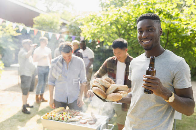 Portrait jeune homme confiant buvant de la bière, profitant du barbecue dans la cour d'été — Photo de stock