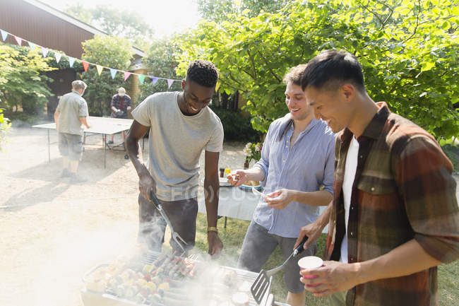 Young men barbecuing in sunny backyard — Stock Photo