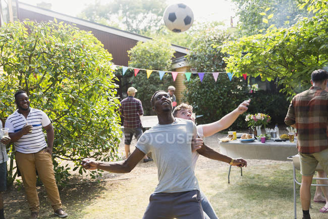 Male friends playing soccer, enjoying backyard summer barbecue — Stock Photo