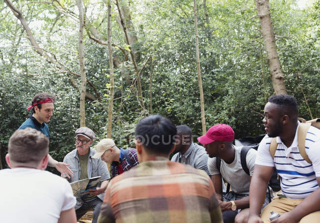 Група чоловіків з картою, що готується до походу в лісі — стокове фото