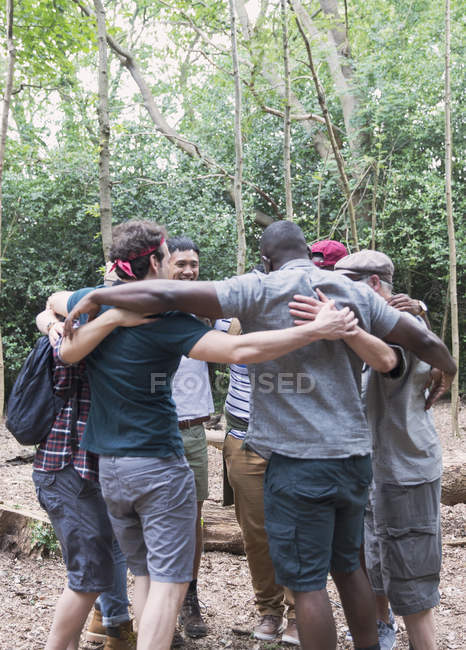 Mens group hugging in huddle, hiking in woods — Stock Photo