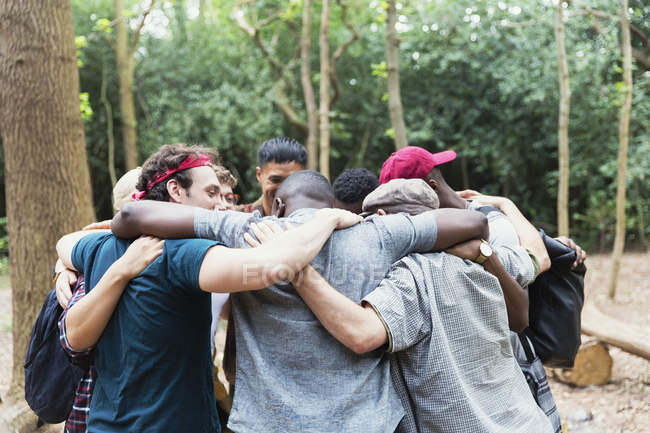 Чоловіки друзі обіймаються в тулубі під час походу в лісі — стокове фото