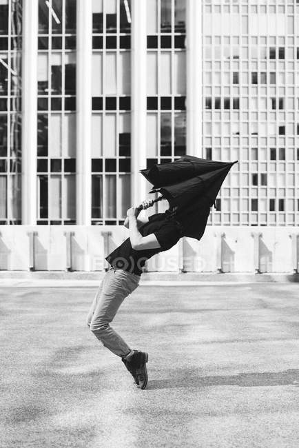 Man dancing with umbrella covering head — Stock Photo