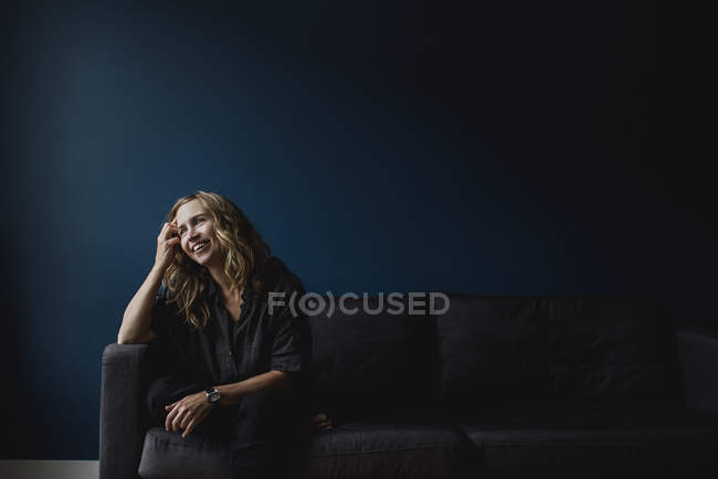 Donna felice seduta sul divano, distogliendo lo sguardo — Foto stock