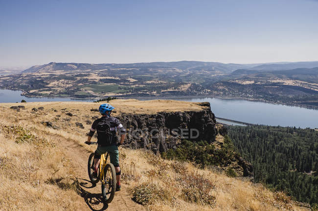 Man mountain biking, enjoying Columbia River view from cliff, Hood River, Oregon, USA — Stock Photo