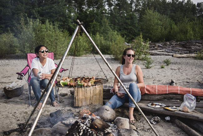 Mulheres relaxantes, desfrutando de churrasco na praia — Fotografia de Stock