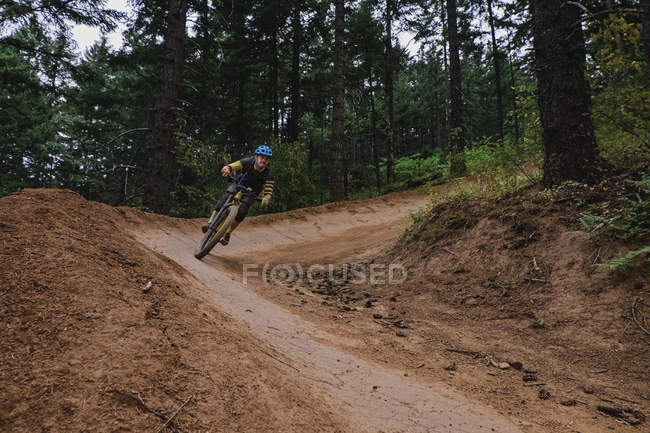 Man mountain biking on dirt trail in woods — Stock Photo