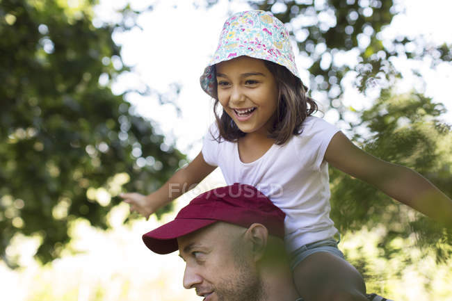 Glückliches, unbeschwertes Mädchen auf den Schultern des Vaters — Stockfoto