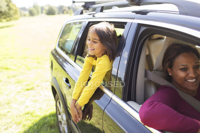 Carefree girl leaning out window of car — Stock Photo