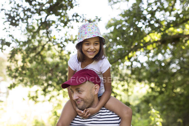 Father carrying daughter on shoulders in park — Stock Photo