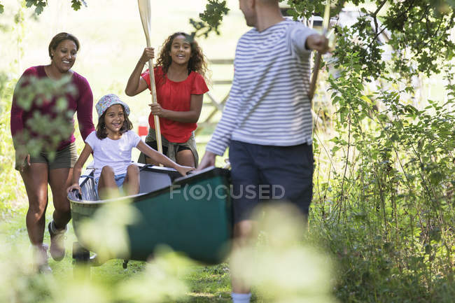 Familia tirando de la canoa en el bosque - foto de stock