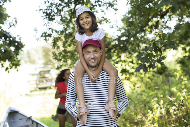 Retrato padre llevando hija en hombros en el bosque - foto de stock