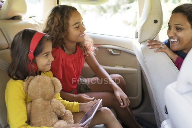 Madre e hijas montando en coche - foto de stock