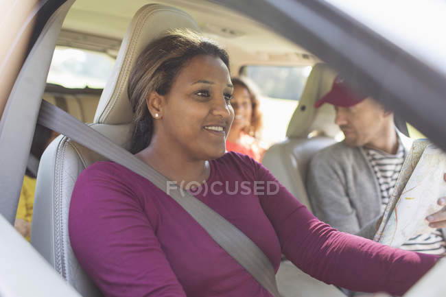 Donna sorridente guida auto con la famiglia in viaggio — Foto stock