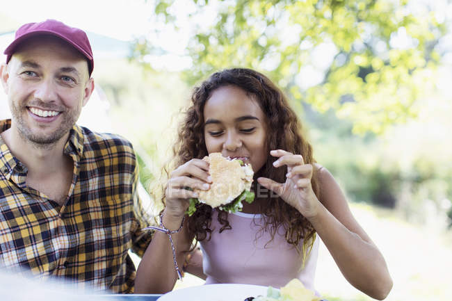 Отец и дочь наслаждаются гамбургером для барбекю — стоковое фото