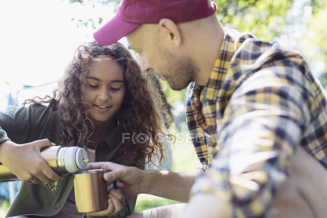 Hija vertiendo café de recipiente de bebida aislada para el padre - foto de stock