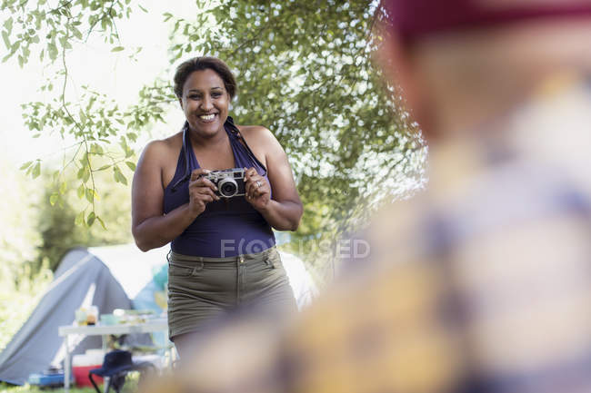 Mulher feliz com câmera no parque de campismo — Fotografia de Stock