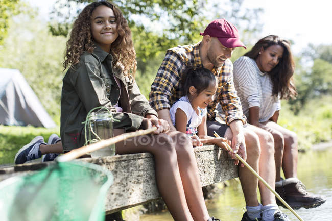 Ritratto sorridente ragazza pesca con la famiglia sul molo — Foto stock
