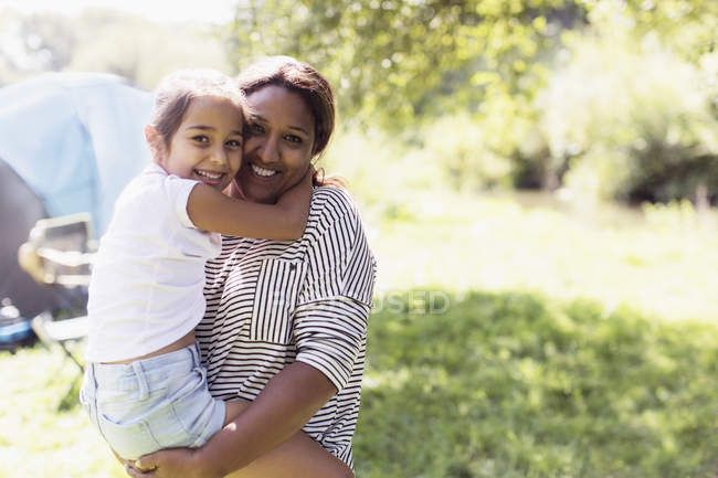Портретна прихильна мати тримає дочку в сонячному кемпінгу — стокове фото