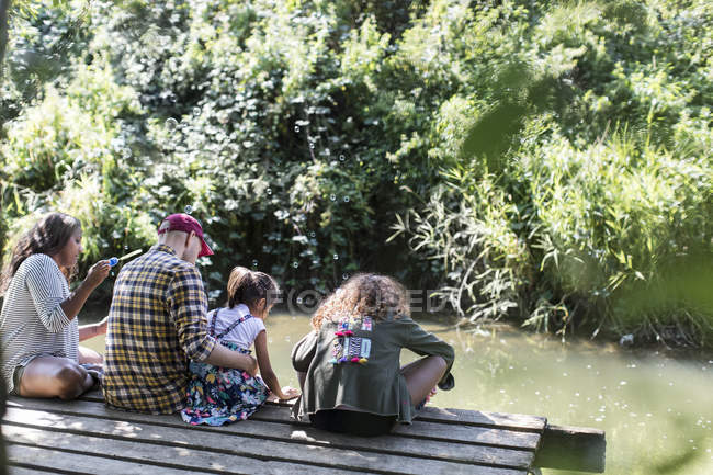 Family relaxing on dock in woods — Stock Photo