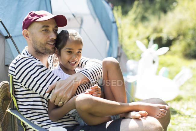 Affectionate father hugging daughter at sunny campsite — Stock Photo