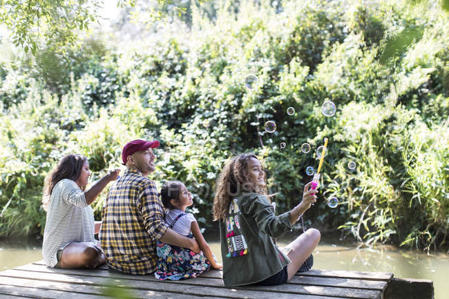 Familie bläst Blasen auf Dock im Wald — Stockfoto