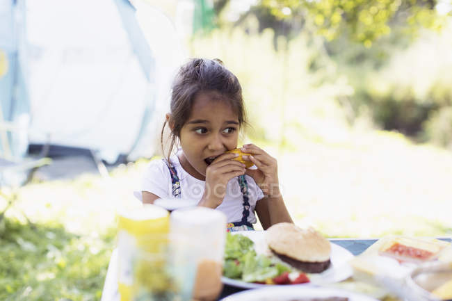 Девушка ест кукурузу в початках в кемпинге — стоковое фото