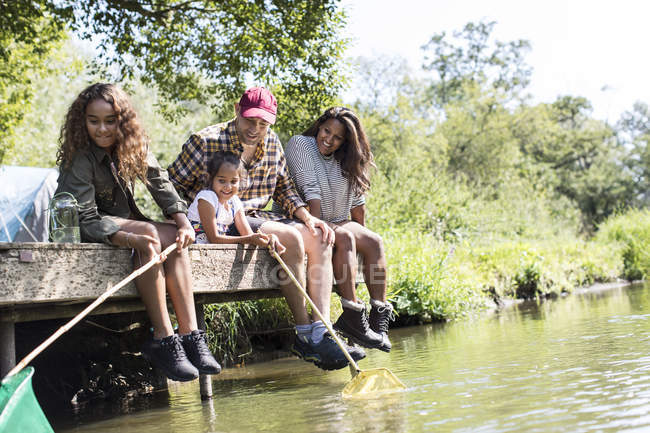Glückliche Familie angelt vom sonnigen Ufer des Flusses — Stockfoto