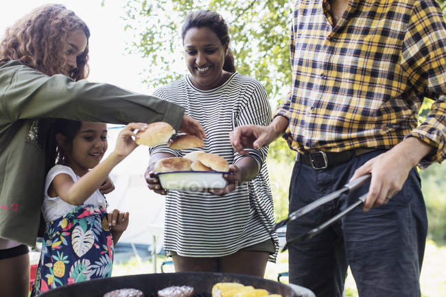 Family barbecuing hamburgers outdoors — Stock Photo