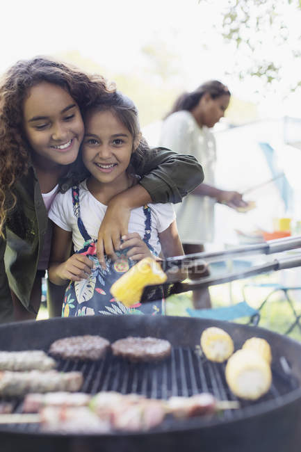 Portrait affectionate sisters enjoying barbecue — Stock Photo