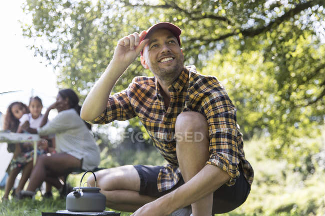 Feliz hombre calentando la tetera en la estufa de camping - foto de stock