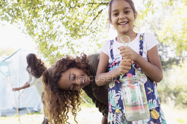Portrait happy sisters catching fish in jar — Stock Photo