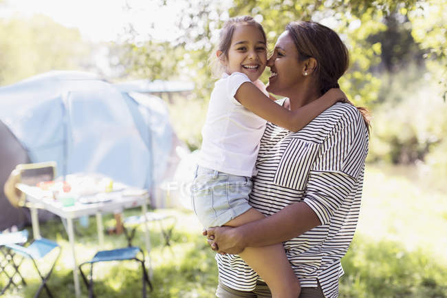 Retrato cariñoso madre e hija abrazándose en el campamento soleado - foto de stock