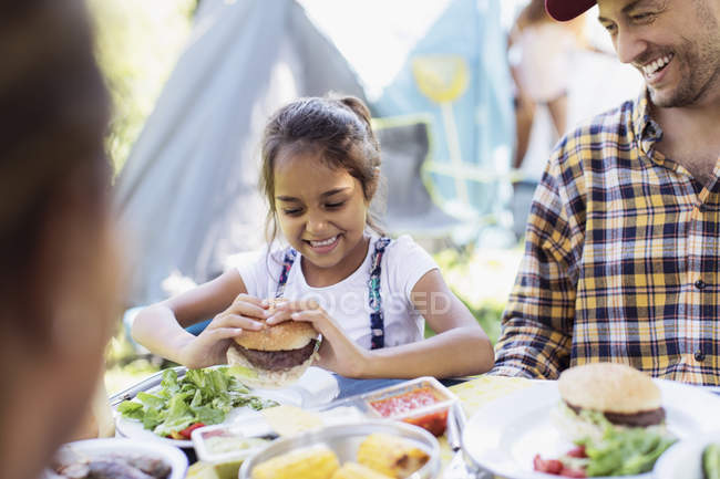 Happy father and daughter eating barbecue hamburgers at campsite — Stock Photo