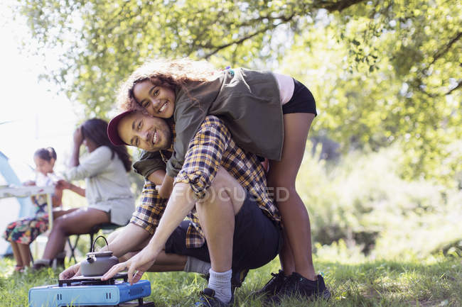 Portrait playful, affectionate daughter hugging father at camping stove at campsite — Stock Photo
