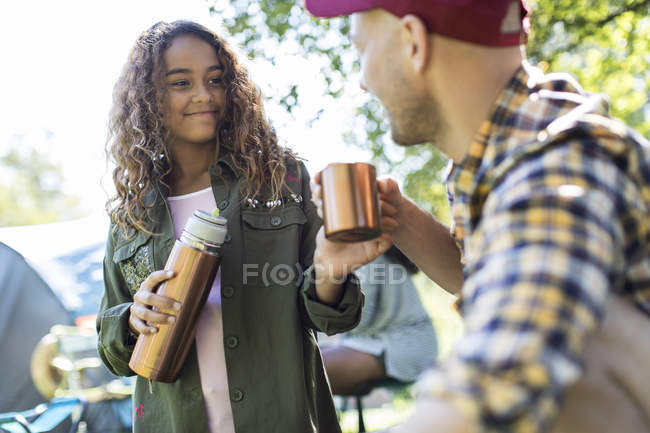 Tochter schüttet Kaffee aus isoliertem Getränkebehälter vom Vater auf Campingplatz — Stockfoto