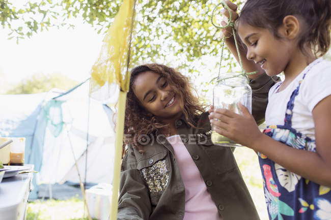 Sisters catching insects in jar at campsite — Stock Photo