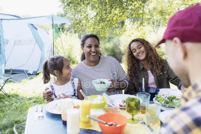Familia feliz disfrutando del almuerzo en la mesa del camping - foto de stock