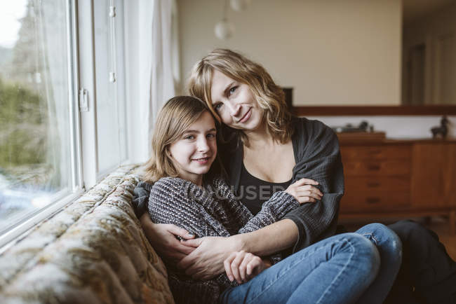 Retrato afetuoso mãe e filha abraçando no sofá da sala de estar — Fotografia de Stock