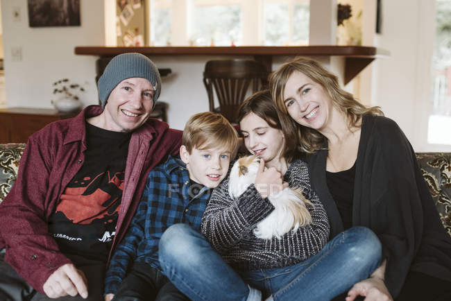 Retrato família feliz com cobaia no sofá sala de estar — Fotografia de Stock