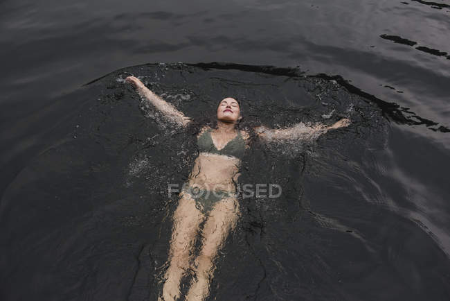 Serena giovane donna in bikini galleggiante nel lago — Foto stock